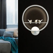 Modern led white wall lamp with circular metal frame and three small white bird figurines for bedroom use