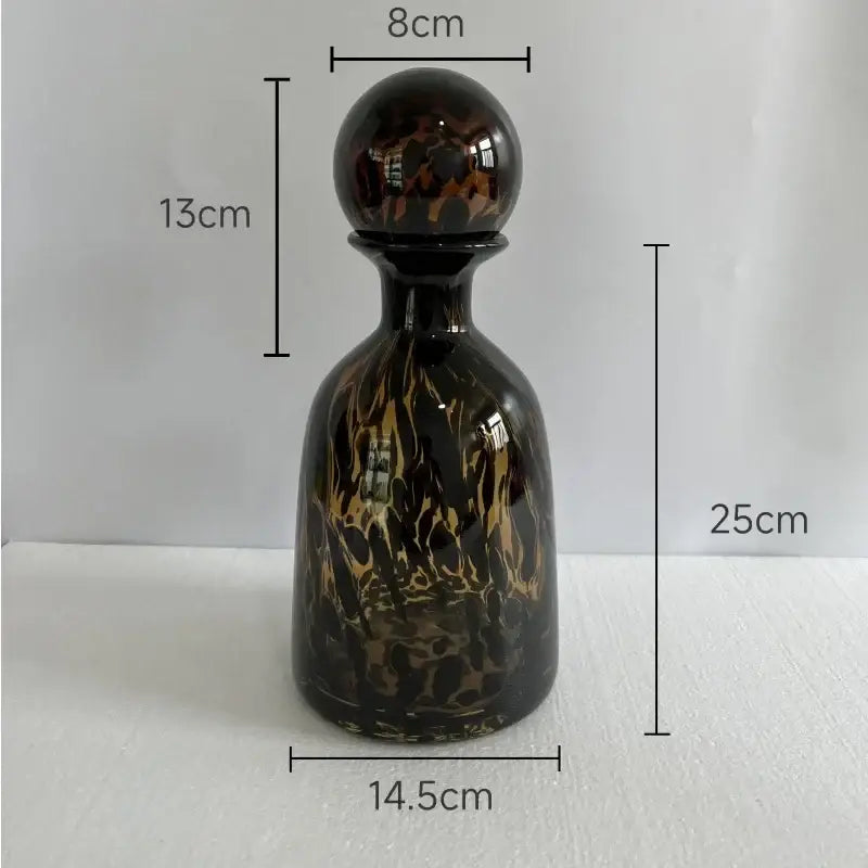 A glossy dark glass decanter with swirling amber and black leopard texture perfect for black and white dining room decorbites