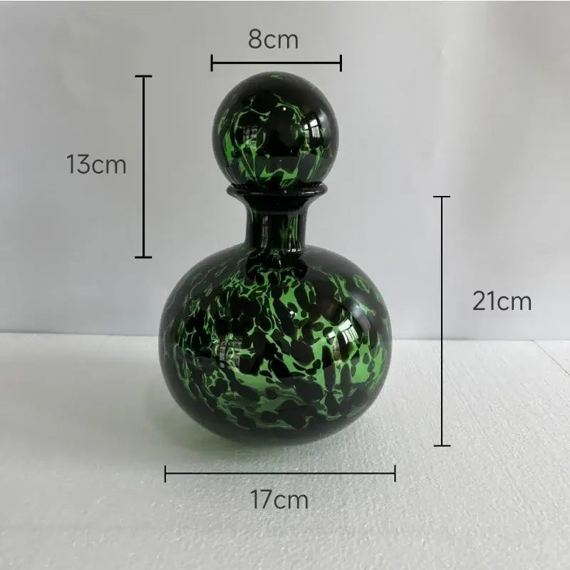 A glossy green and black marbled glass perfume bottle with spherical stopper showcasing decorbites leopard texture design