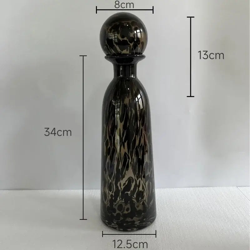 A sleek black glass decanter with glossy gold marbled leopard texture and spherical stopper for dining room decorbites leopard texture