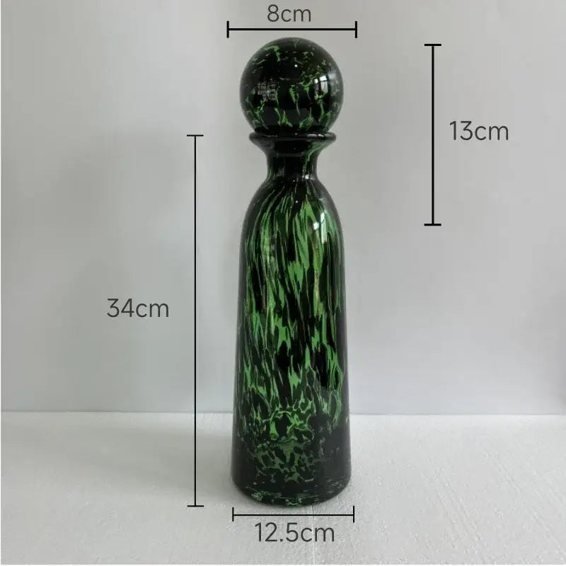 A tall slender green and black marbled glass decanter with a spherical stopper for decorbites leopard texture decor