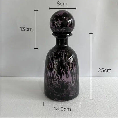 A sleek 25cm dark purple glass decanter with glossy black swirling leopard texture patterns and an ornate spherical stopper