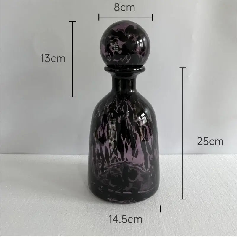 A sleek 25cm dark purple glass decanter with glossy black swirling leopard texture patterns and an ornate spherical stopper