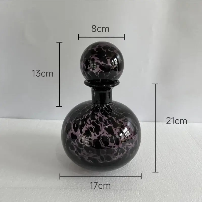 A glossy black glass perfume bottle with marbled purple stopper in modern leopard texture glass decorbites style