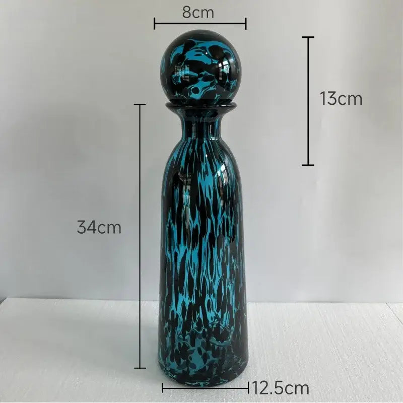 A 34cm tall glass decanter with a swirling teal and black leopard texture glass pattern and a spherical stopper