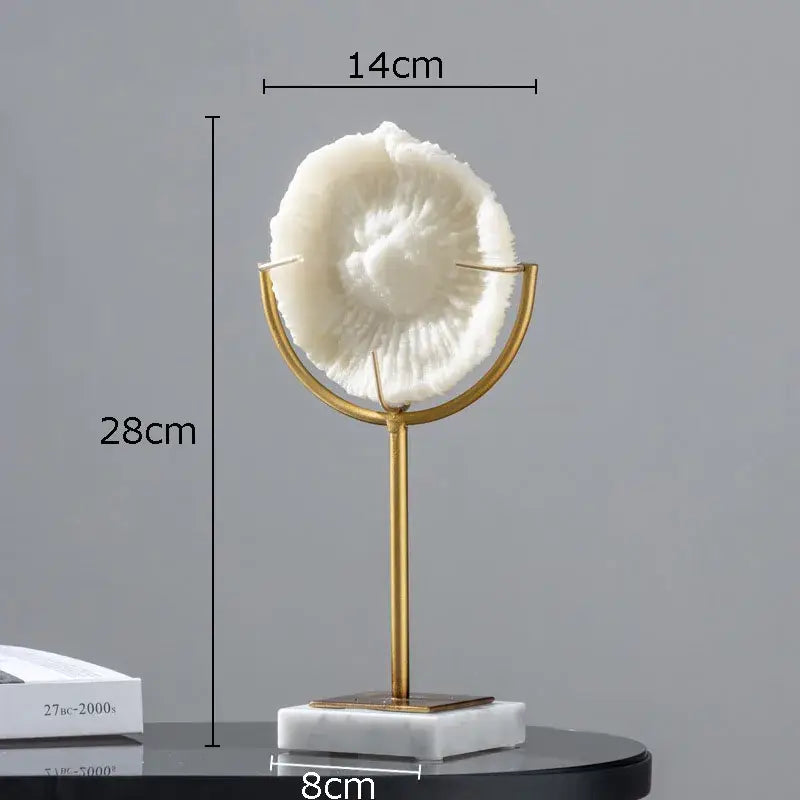 A white textured seashell coral resin statue on a gold-toned stand with a marble base for living room decor