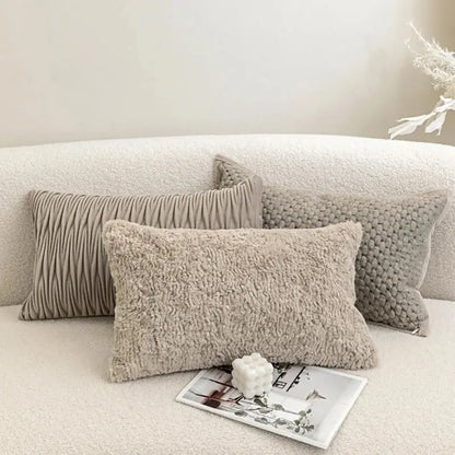 Three beige textured throw pillows with ribbed fuzzy and knitted cushion covers on a soft white couch decorbites light grey