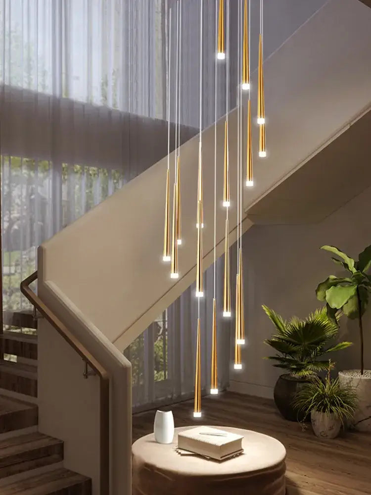 Golden cylindrical pendant lights of decorbites loft black led stair chandelier hang above a modern staircase