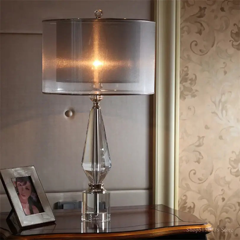 Modern luxe gray and crystal table lamp featuring a faceted clear glass base and translucent gray drum shade for bedroom lighting