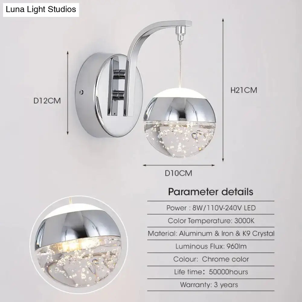 Modern luxurious crystal led wall sconce with chrome finish, curved arm, and illuminated k9 crystal bubble glass globe