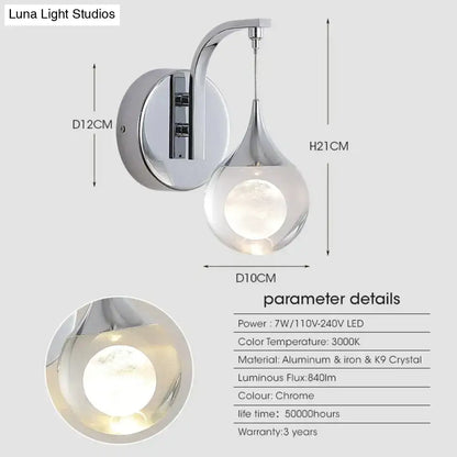 Modern luxurious crystal led wall sconce with chrome finish, curved arm, and teardrop-shaped crystal glass shade for bedroom