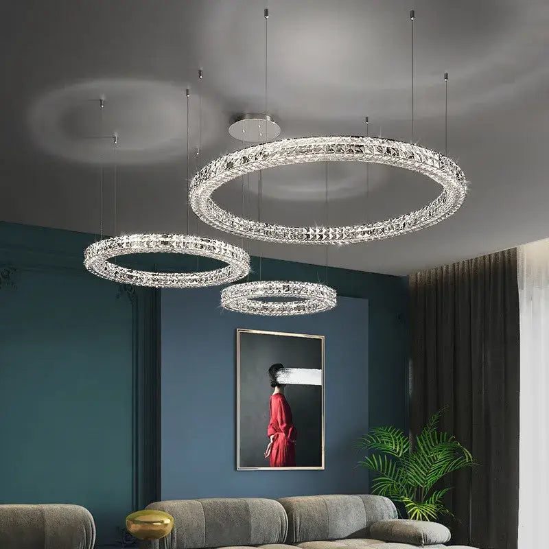 Three elegant crystal led chandeliers with chrome decorbites finish hang in a modern luxury dining room setting