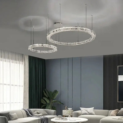 Two elegant crystal led chandelier circular fixtures with chrome decorbites finish hang in a dining room setting