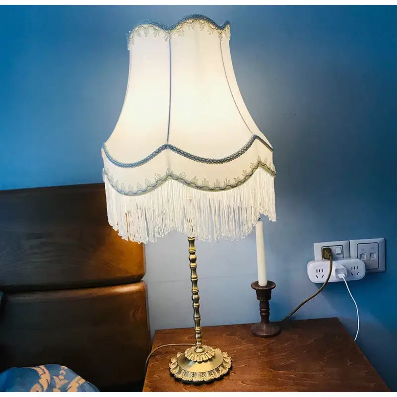 Antique brass table lamp with modern luxury cream fringed cloth lampshade featuring blue embroidered trim by decorbites fringed cloth