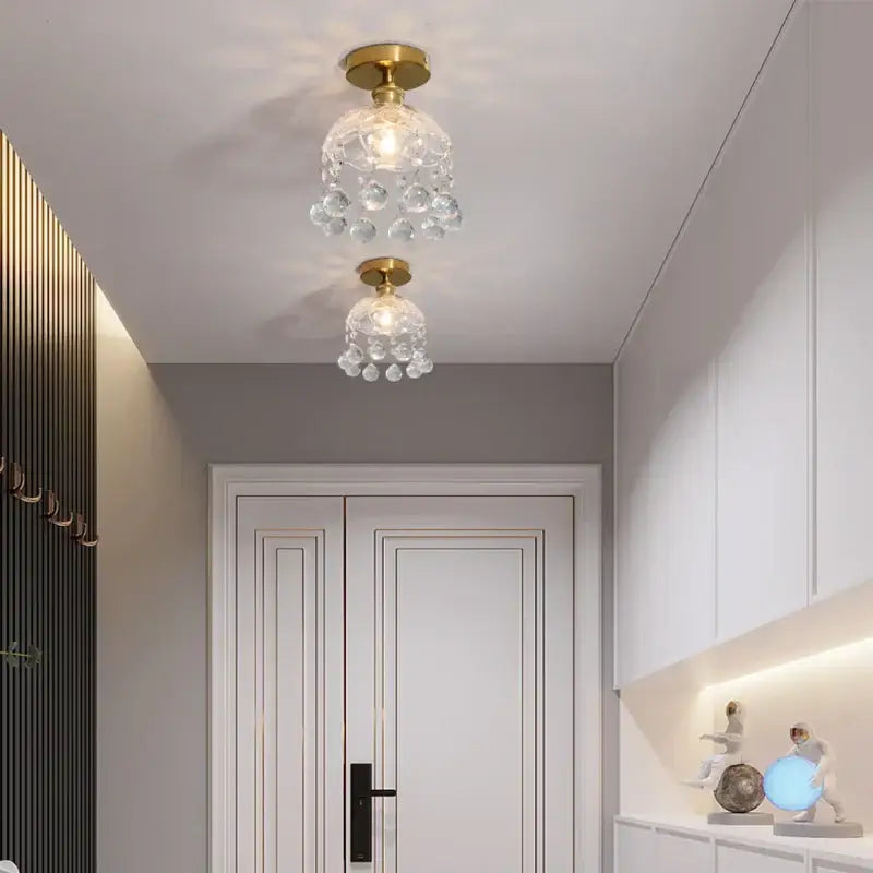 Two elegant decorbites crystal glass ceiling lamps with gold-finished bases and dangling clear glass orbs for living room
