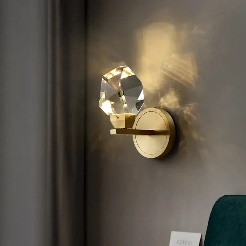 A modern luxury gold crystal led wall sconce with a faceted globe and polished brass base for elegant decorbites crystal led lighting
