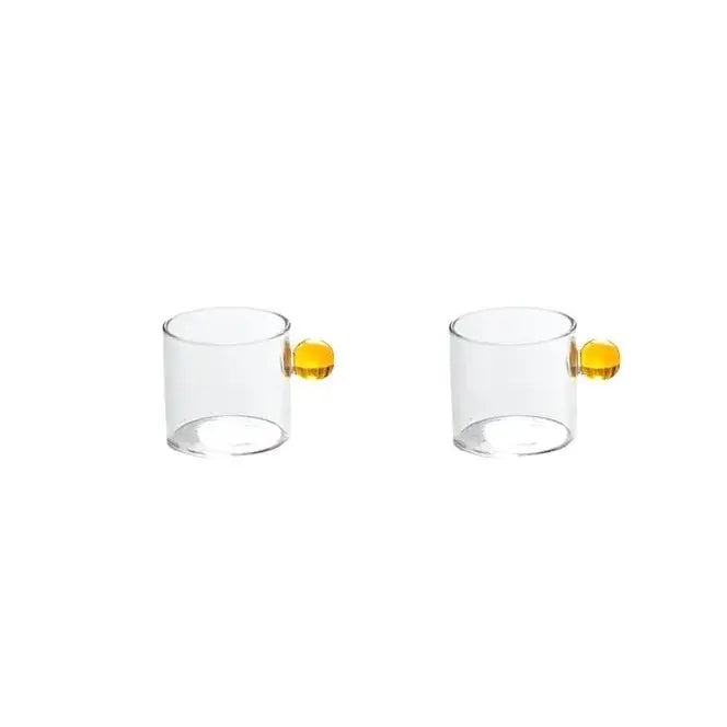 Modern marble sphere glass espresso cups with vibrant yellow spherical handles and matching glass saucers for kitchen use