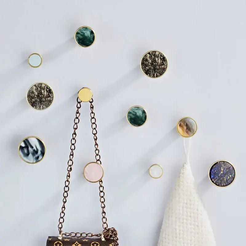 Gold-rimmed circular towel hooks with marbled stone centers in green brown pink blue and white decorbites brushed gold design