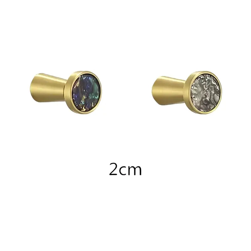 Gold-toned cabinet knobs with circular iridescent stone inlays complement decorbites brushed gold towel hook bathroom decor