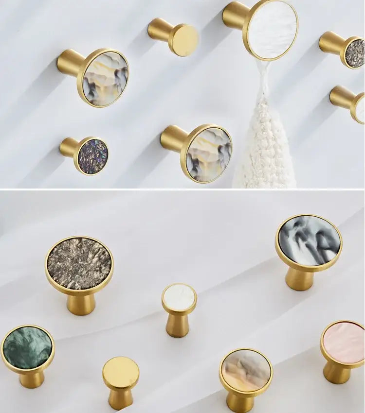 Gold-toned cabinet knobs with circular marble-patterned inserts complement decorbites brushed gold towel hooks