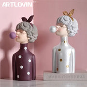 Two stylized resin bubble gum girl statues in maroon and silver polka-dot dresses for modern bedroom decor