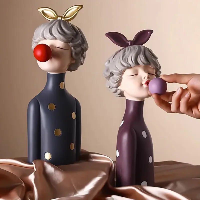 Two stylized bubble gum girl statues with gray hair in navy blue and purple outfits for modern bedroom decor