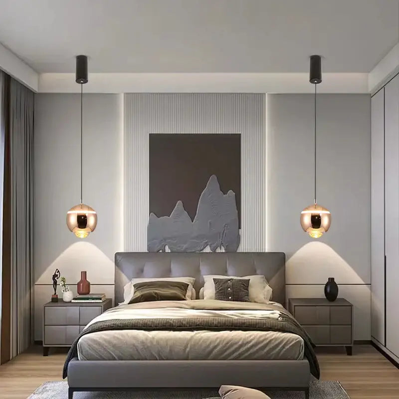 Modern gray upholstered bed with tufted headboard and layered bedding illuminated by matte ball pendant lights
