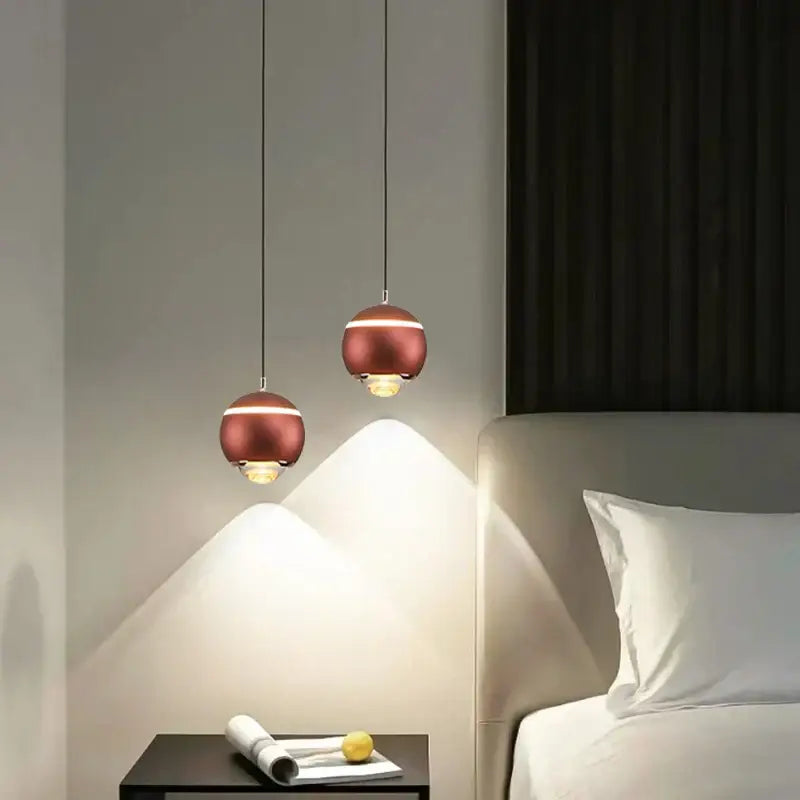 Two modern copper-toned matte ball pendant lights with a minimalist design hang above a bedside table