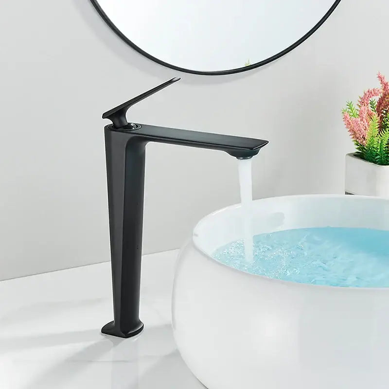 Modern matte black basin mixer with black matte finish and sleek tall slender spout flowing water into white basin