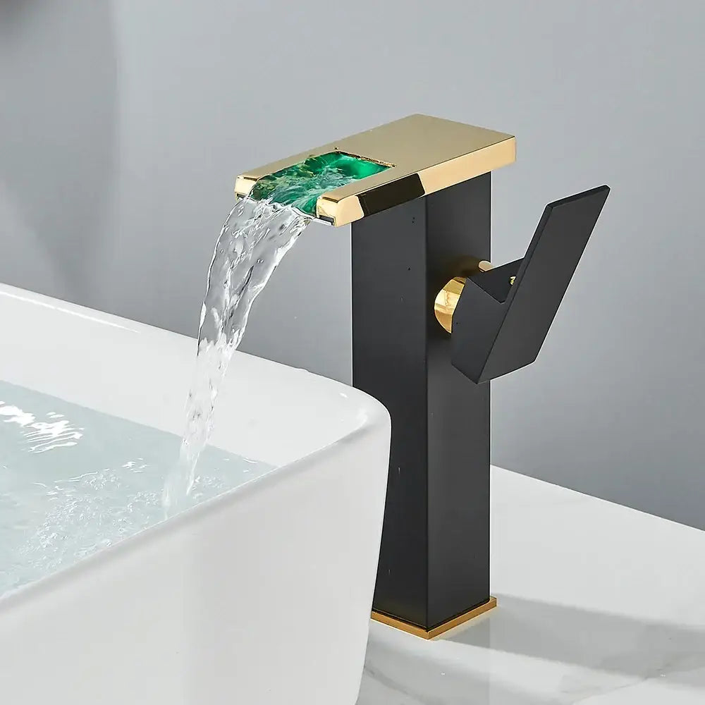 Modern matte black bathroom faucet set featuring a sleek black waterfall faucet with gold trim and a green glass panel