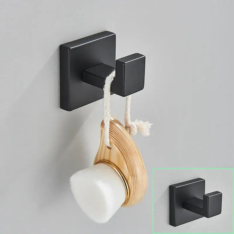 Modern matte black bathroom hardware set showing a black matte square double hook holding a wooden and white soap brush