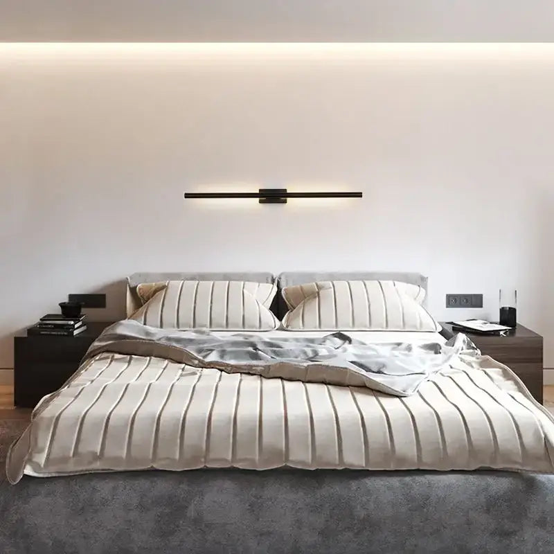 A modern bed with upholstered headboard and beige bedding illuminated by a matte black and brass gold led wall light decorbites brass gold