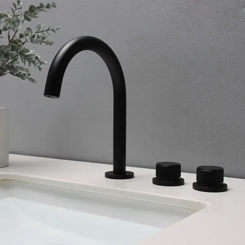 Modern matte black basin faucet with curved spout and brushed gold handles for bathroom sink use