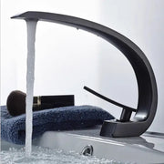 Modern matte black and gold modern basin faucet with sleek curved design and flowing water stream for bathroom use