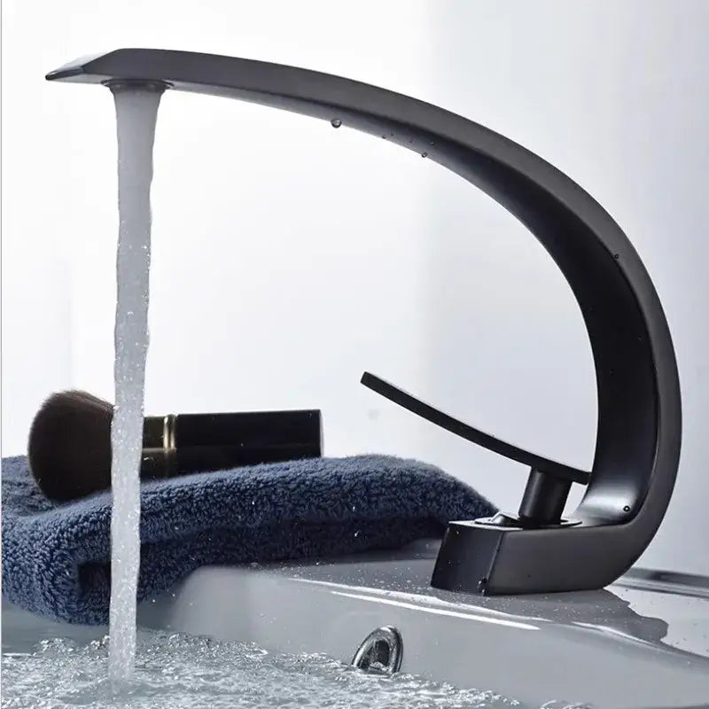 Modern matte black and gold modern basin faucet with sleek curved design and flowing water stream for bathroom use