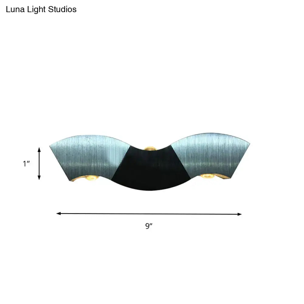 A sleek modern sconce light with aluminum wave design and black accent offering warm white lighting for bedrooms