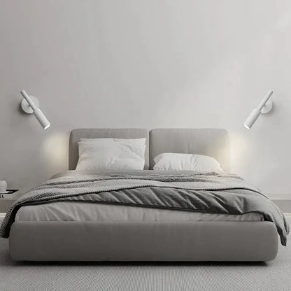 Modern matte black led wall lamp reading light shown above a gray upholstered bed with matching headboard and footboard