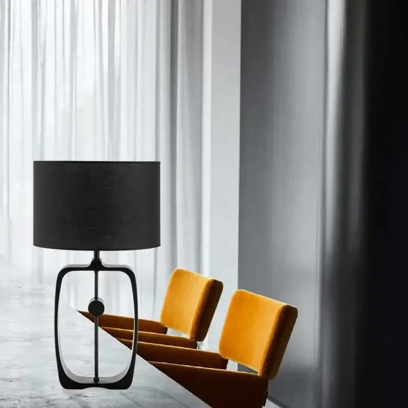 Modern matte black metal table lamp with cylindrical fabric shade and oval frame for living room decorbites designer