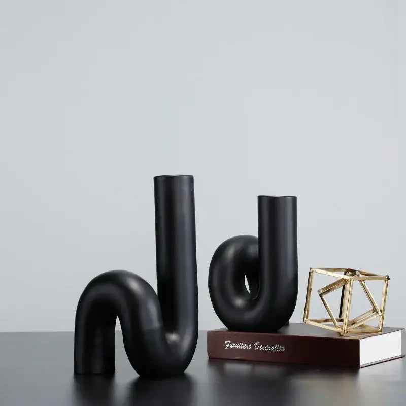 Two sleek matte black ceramic vases with twist knot black pipe geometric design for modern living room decor