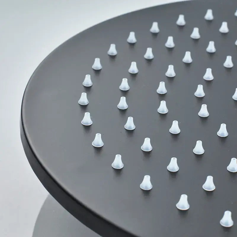 Black round brass rain shower head with evenly spaced white conical nozzles in a modern matte finish bathroom fixture