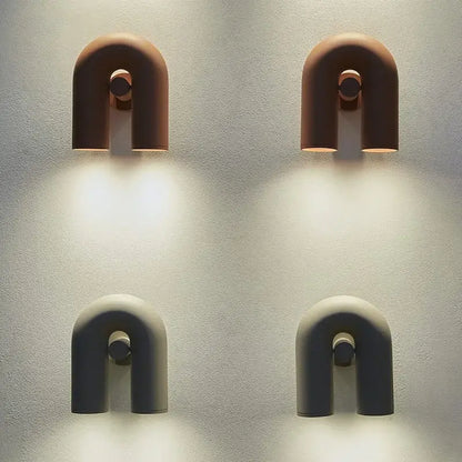 Two minimalist u-shaped wall lamps in terracotta and matte gray ceramic with circular accents for modern tube wall decorbites cirkus tube design