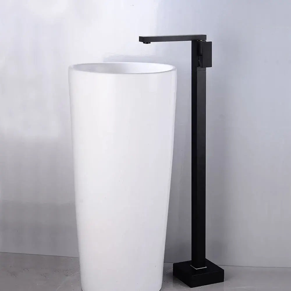 Modern matte black tall basin faucet with a sleek minimalist design paired with a white cylindrical pedestal sink