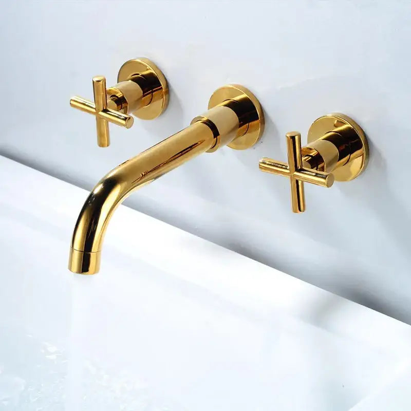 Gold-colored wall-mounted dual handle bathroom faucet with cross-shaped handles and a sleek modern design