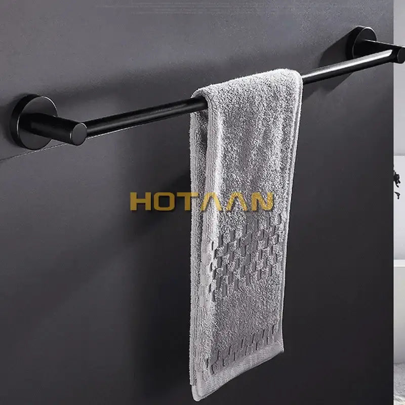 A soft gray towel hangs on a modern matte black wall mounted towel bar with wood accents for bathroom use