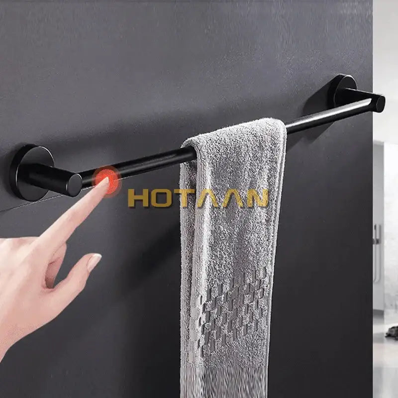 Modern matte black wall mounted towel bar with wood accents holding a gray textured towel in bathroom setting