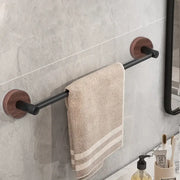 Beige towel with two stripes hangs on a modern matte black wall mounted towel bar with round wooden end caps