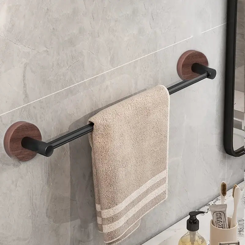 Beige towel with two stripes hangs on a modern matte black wall mounted towel bar with round wooden end caps
