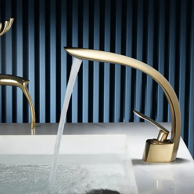 Gold-toned sleekly curved waterfall basin faucet with single handle mixer for modern bathroom use