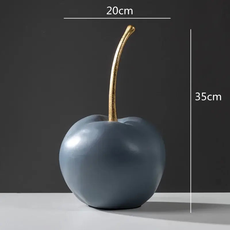 A sleek matte gray ceramic cherry figurine with a polished gold stem complements modern blue resin apple ornaments