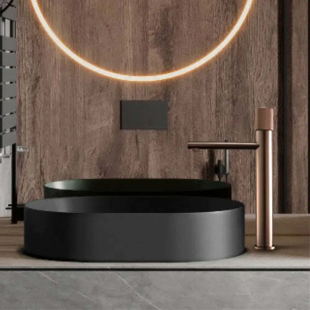 Modern matte bronze basin faucet with textured handles paired with a matte black oval sink for minimalist kitchen use